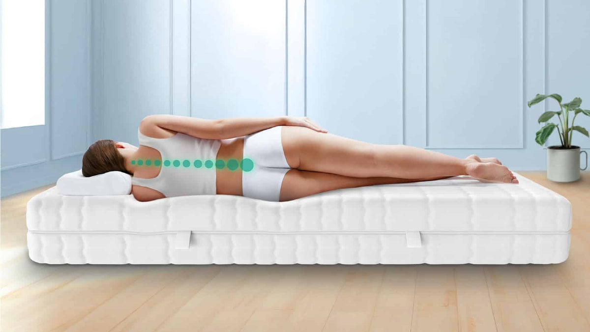 Eine Person liegt seitlich auf einer Matratze, die eine ergonomische Körperhaltung unterstützt. Eine Linie zeigt die Ausrichtung der Wirbelsäule an.