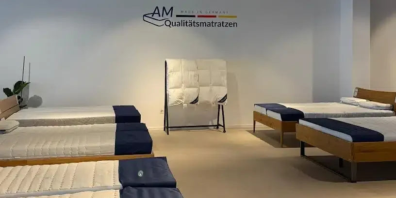 Ausstellungsfläche des Showrooms in Zürich mit Matratzen von AM Qualitätsmatratzen und Logo an der Wand.