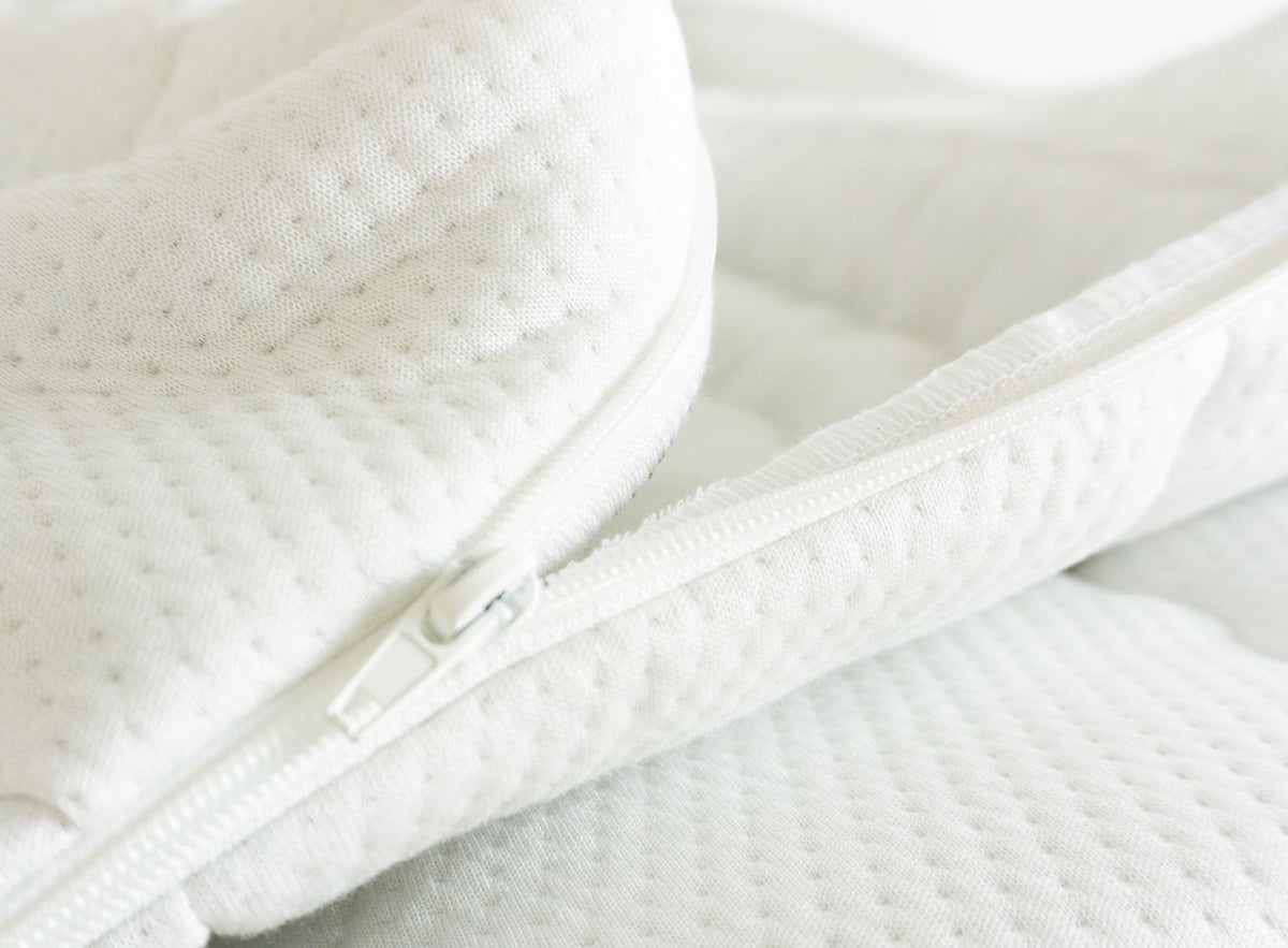 Detailaufnahme eines weißen Matratzenbezugs aus Tencel mit Reißverschluss und strukturierter Oberfläche.